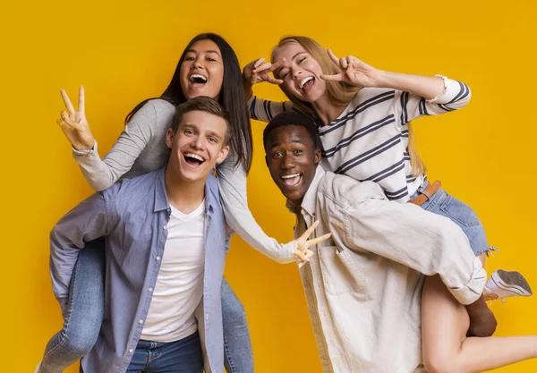 Dois casais adolescentes internacionais se divertindo sobre fundo amarelo — Fotografia de Stock