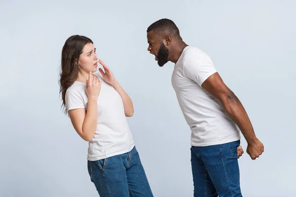 Vzteklý afro chlap emocionálně křičí na svou vyděšenou přítelkyni, obviňuje ji — Stock fotografie