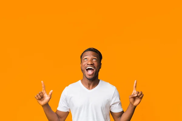 Tipo excitado señalando los dedos de pie sobre fondo naranja, Estudio — Foto de Stock