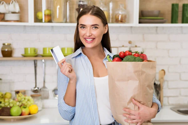 Женщина с кредиткой и сумкой, полной свежих овощей — стоковое фото