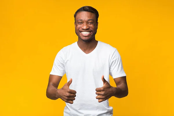 Afro Man Gesturing Thumbs-Up posando sobre fundo de estúdio amarelo — Fotografia de Stock