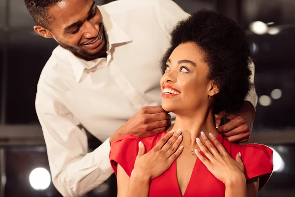Loving Afro chłopak daje naszyjnik dziewczyny podczas randki w restauracji — Zdjęcie stockowe