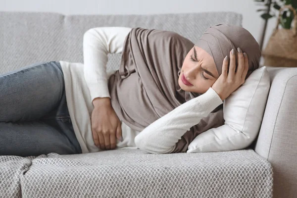 Sick Muslim Woman Having Abdominal Pain, Lying On Couch At Home — Stock Photo, Image