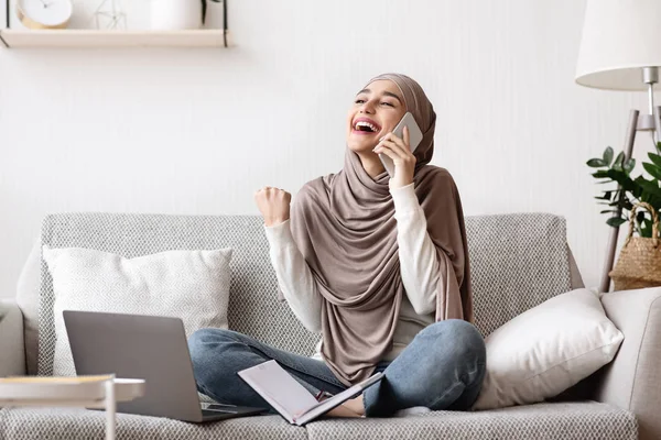 Perempuan arab yang ceria dalam jilbab berbicara di ponsel dan merayakan keberhasilan — Stok Foto