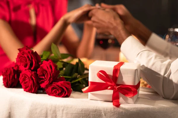 Antecedentes románticos de la pareja sosteniendo las manos, regalos acostados en la mesa — Foto de Stock
