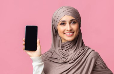 Güzel bir Arap kadının ellerinde siyah ekranlı akıllı telefon.
