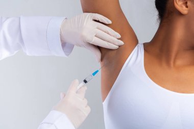 Doktor koltuk altı bölgesinde botulinyum toksini enjekte ediyor.