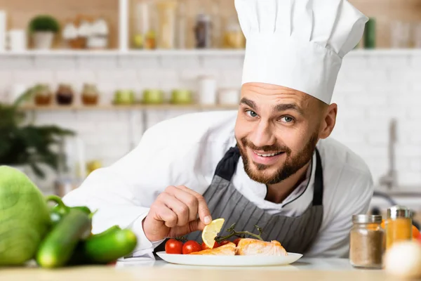 Profissional Chef Man chapeamento prato de salmão trabalhando na cozinha — Fotografia de Stock