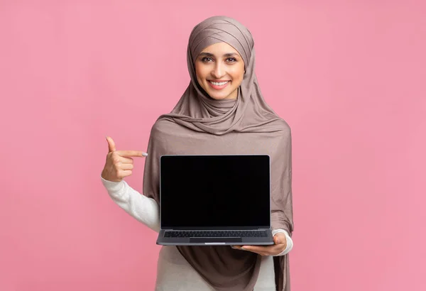 Feliz chica musulmana sosteniendo portátil con pantalla negra en la mano —  Fotos de Stock