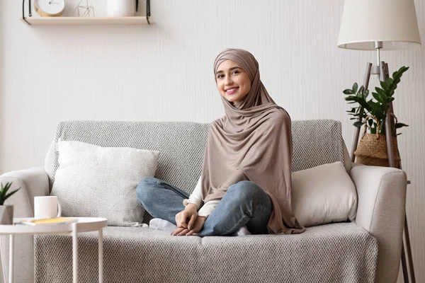 Happy arabic girl in hijab posing on sofa at home — Stok Foto