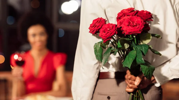 Irreconhecível homem segurando rosas ter data com namorada no restaurante — Fotografia de Stock