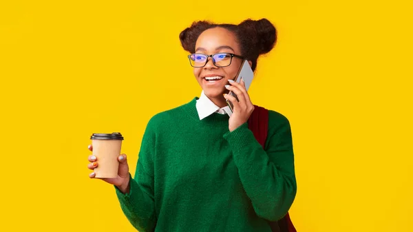 Happy afro teenager talking on cellphone holding coffee — Stock Photo, Image