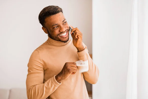 Χαρούμενος τύπος έχοντας τηλεφωνική συνομιλία στέκεται κοντά στο παράθυρο στο σπίτι — Φωτογραφία Αρχείου