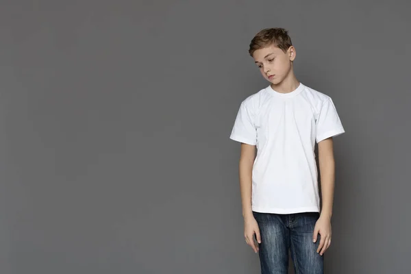 Sad teen boy standing alone, grey studio background — 스톡 사진