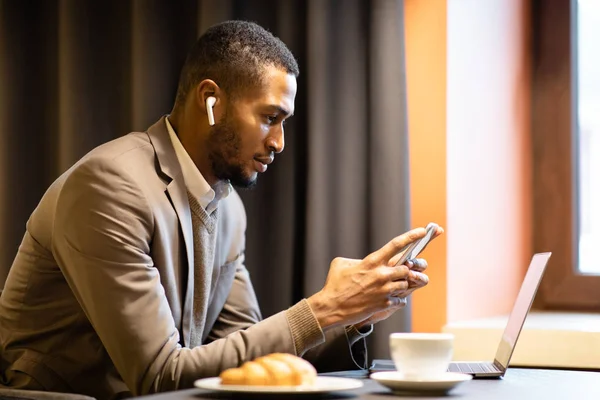 Πορτρέτο του πολυάσχολου μαύρου άντρα χρησιμοποιώντας το κινητό τηλέφωνο και τον υπολογιστή — Φωτογραφία Αρχείου