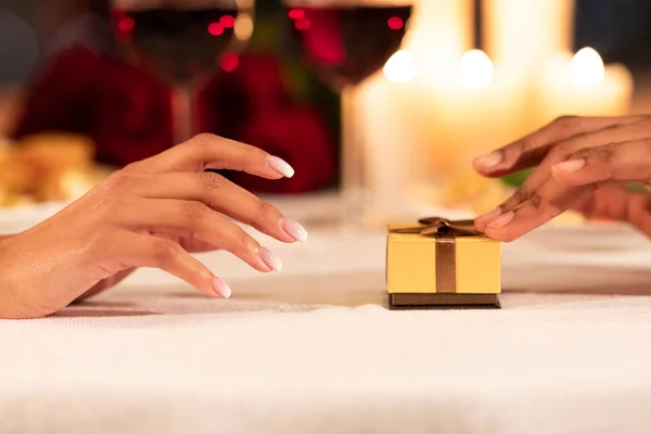 Mâini de sex masculin împingând cutie cadou pentru prietena pe masa restaurant — Fotografie, imagine de stoc
