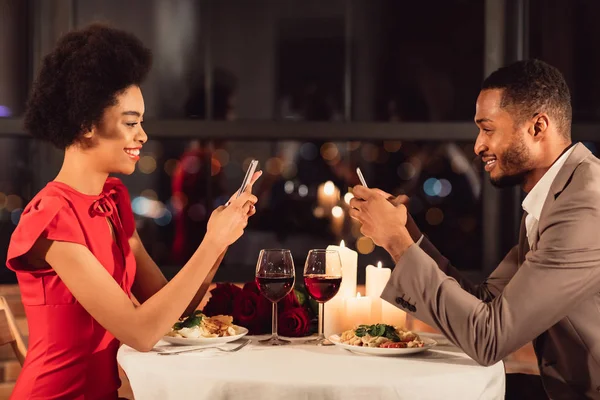 Par som använder mobiltelefoner sms under romantisk middag i Fancy Restaurant — Stockfoto