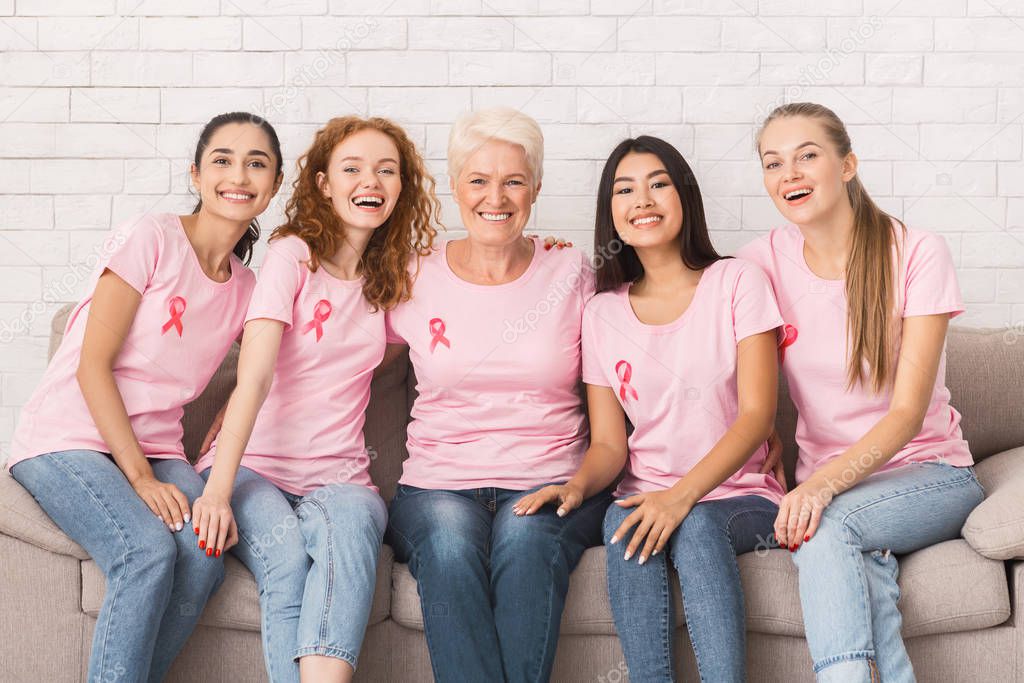 Women In Pink Breast Cancer T-Shirts Embracing Sitting On Sofa