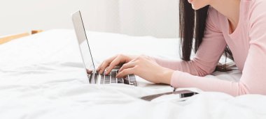 Dizüstü bilgisayarda yazan kadın gazeteci, evde yatakta yatıyor.