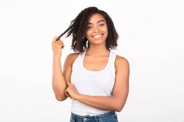 Siyah kız kameraya bakarak saçlarıyla oynuyor.