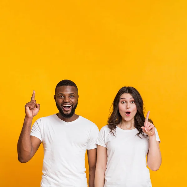 Multiracial par pekar upp på kopia utrymme på gul bakgrund — Stockfoto