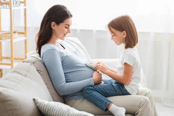 Menina pré-escolar brincando com ela esperando mãe barriga — Fotografia de Stock