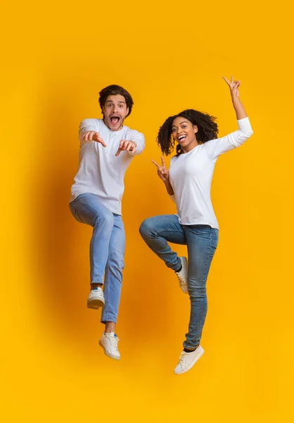 Playful multiracial couple fooling together and jumping in the air — 스톡 사진