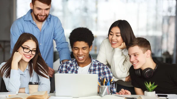 Happy college classmates using laptop in library — Stock Photo, Image