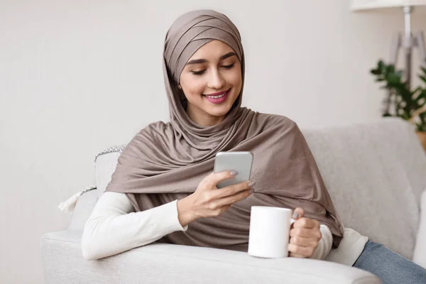 Smiling Girl In Hijab Resting At Home With Smartphone And Coffee — Stok Foto