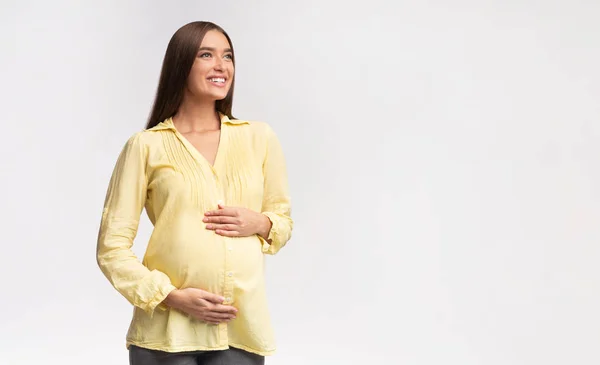 Femme enceinte toucher le ventre en regardant l'espace de copie, fond blanc — Photo