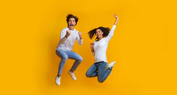 Overjoyed multiracial couple jumping in the air and celebrating success — 스톡 사진