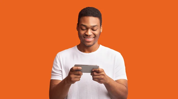 Interessanter Afro-Typ mit Smartphone über orangefarbenem Hintergrund — Stockfoto