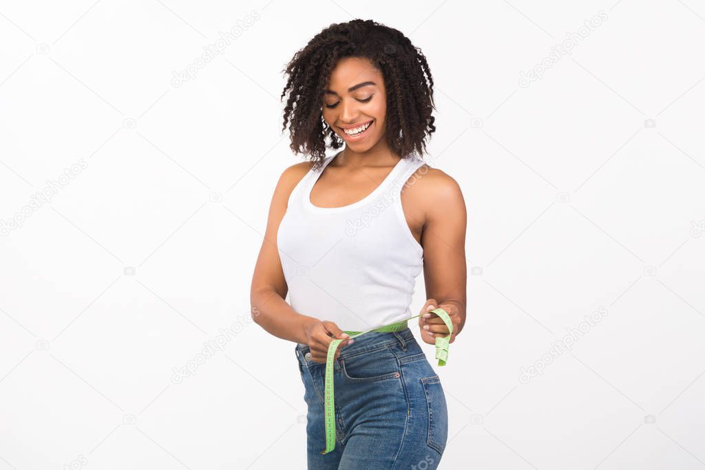 Portrait of african american woman measuring waist