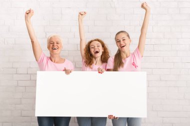 Üç Pembe Tişörtlü Kadın Beyaz Duvarın Üzerinde Poster Tutuyor