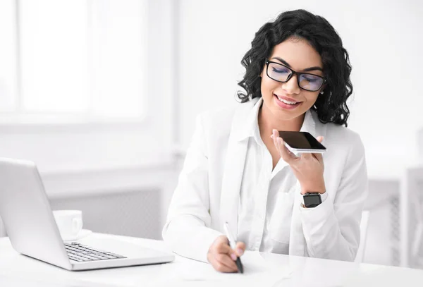 Smiling hispanic woman using voice assistant on phone