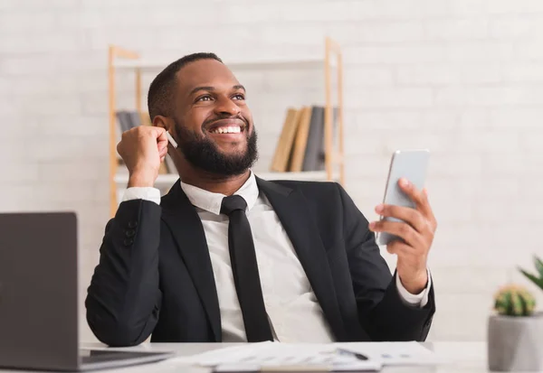 Hombre de negocios alegre escuchando música con auriculares, usando un teléfono inteligente — Foto de Stock