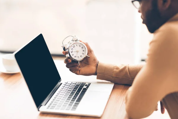 Irriconoscibile afro uomo d'affari in possesso di orologio utilizzando il computer portatile — Foto Stock