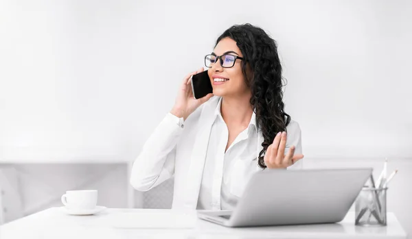 Glimlachend Spaans meisje aan de telefoon op kantoor — Stockfoto