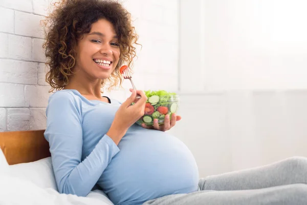 Un bocadillo saludable. Afro chica embarazada disfrutando de ensalada de verduras frescas — Foto de Stock