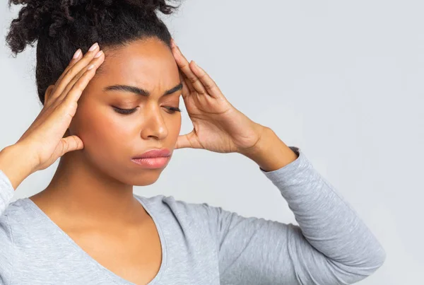 Smutna afro dziewczyna ma ból głowy, masując jej skronie — Zdjęcie stockowe