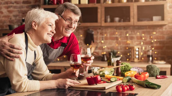 Alegre seniors disfrutando de vino blanco en la cocina —  Fotos de Stock