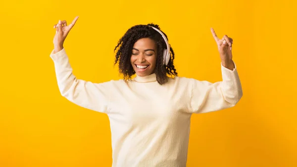 Glimlachende afro vrouw luisteren naar muziek en dansen — Stockfoto