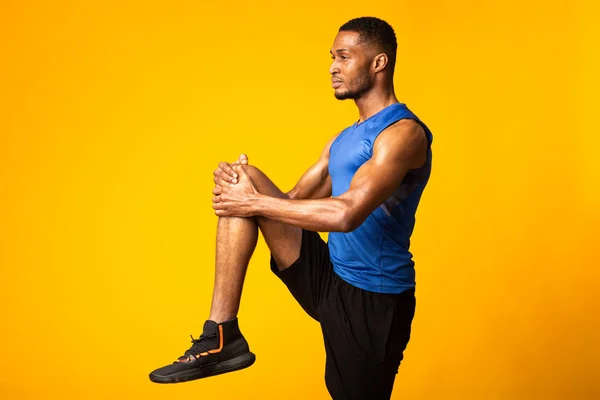 Молодий чорний спортсмен високо тримає коліно — стокове фото