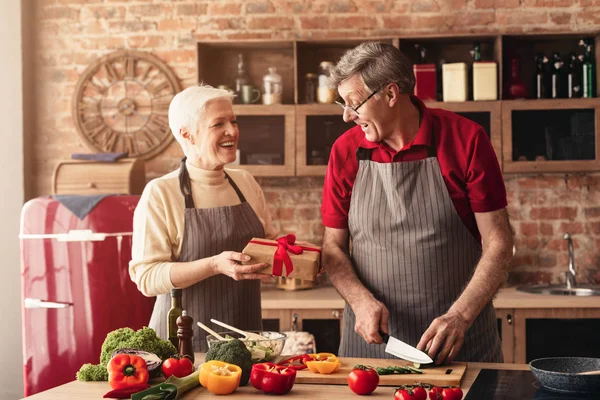 Seniorin schenkt Mann in Küche Geschenkbox — Stockfoto