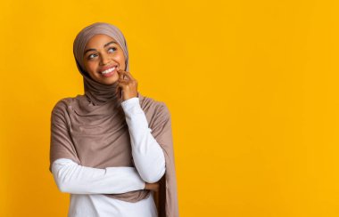 Sarı arka planda tesettürlü düşünceli siyah müslüman kız portresi