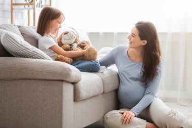 Dost canlısı aile, hamile anne ve küçük kız birlikte vakit geçiriyorlar.