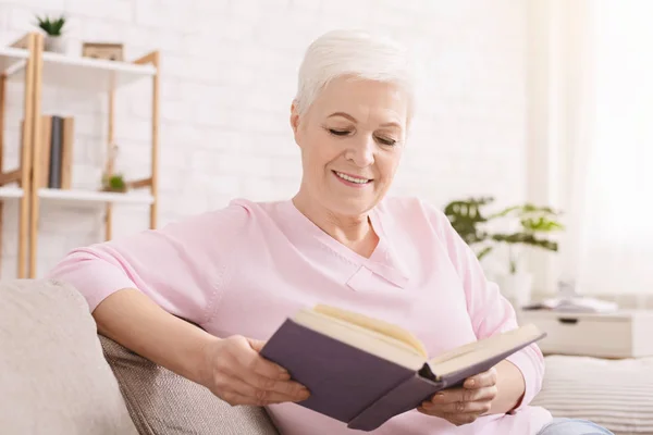 Pozitív idős nő élvezi könyv otthon — Stock Fotó