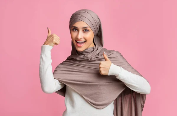 Счастливая мусульманка в хиджабе, жест пальцем вверх обеими руками — стоковое фото