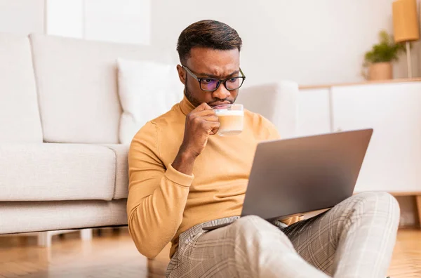 Ondernemer met behulp van laptop met koffie zitten op de vloer thuis — Stockfoto