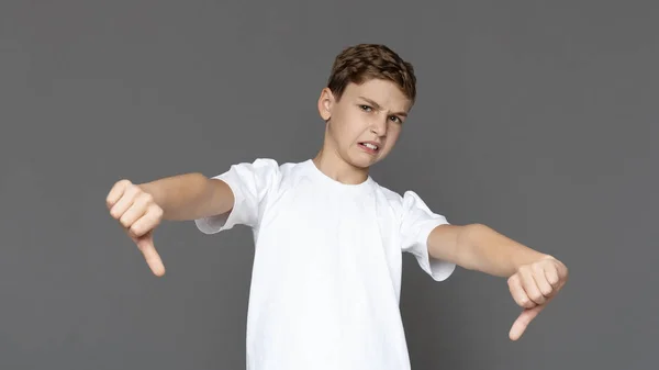 Descontente adolescente menino gestos polegares para baixo com ambas as mãos — Fotografia de Stock